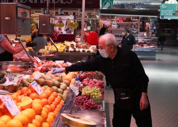 Un cliente señala la pieza de fruta que quiere en una frutería del Mercado Central de Valencia, España. | Iván Terrón,  Europa Press.