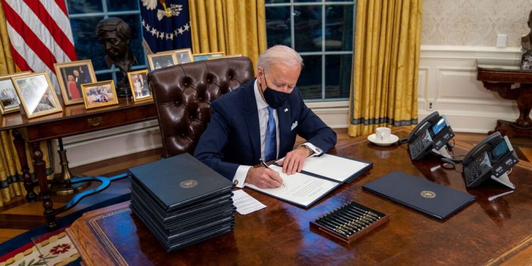 El presidente de EEUU, Joe Biden, firma un documento desde el Despacho Oval de la Casa Blanca.