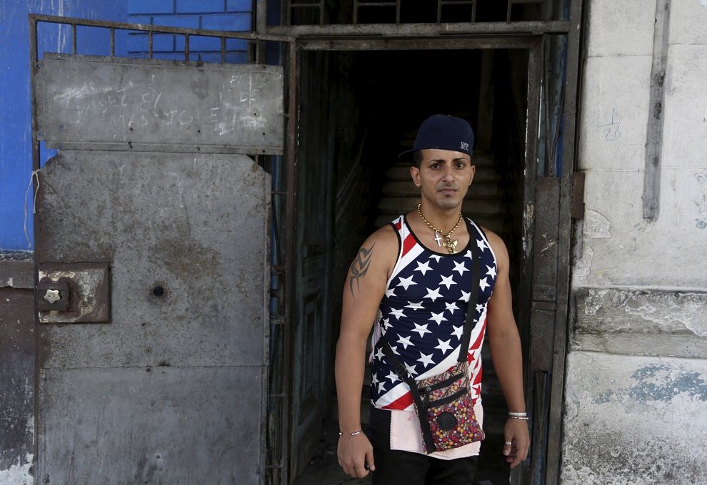 a man wearing a shirt with the u.s flag stands on a street in havana