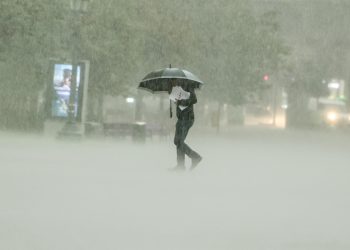 Persona cruza una calle bajo un aguacero. - Fuente externa.