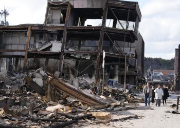 Personas caminan junto a restos quemados de estructuras de edificios tras un terremoto en Wajima, prefectura de Ishikawa (Japón), el 4 de enero de 2024. EFE